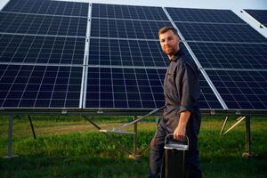Side, view,, cleaning service. Man is working with solar panels outdoors at daytime photo