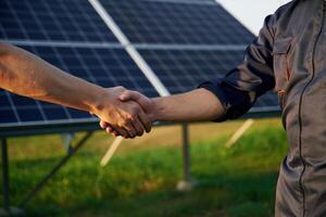 Close, up view of handshake against solar panels outdoors photo