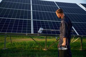 Side,, view, cleaning service. Man is working with solar panels outdoors at daytime photo