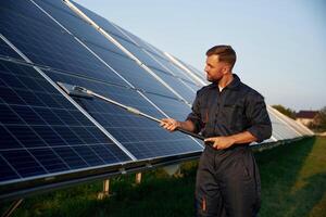 Keep it ,clean. Man is working with solar panels outdoors at daytime photo