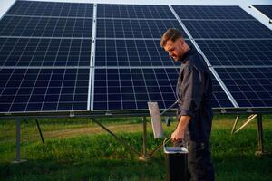 Side, view, cleaning service. Man is working with solar panels outdoors at daytime photo