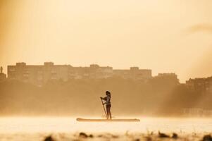 Illuminated by sunlight.,,,, Girl kid is on the sup board, on the lake photo