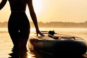 Black,, silhouette, sunset, illuminated. Young woman is with the sup board on the lake photo
