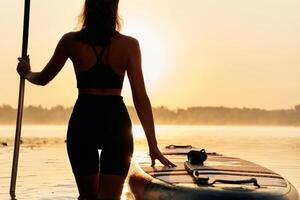 Majestic sunset,,,, standing and looking. Young woman is with the sup board on the lake photo