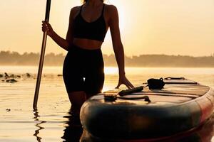 Almost,, evening time, sunset. Young ,woman is with the sup board on the lake photo