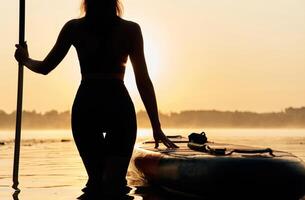 Black,, silhouette, sunset, illuminated. Young, woman is with the sup board on the lake photo