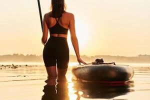 Almost ,evening time, sunset. Young ,,woman is with the sup board on the lake photo