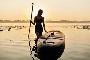 Calm and peaceful, standing ,,,and ,posing. Young woman is with the sup board on the lake photo