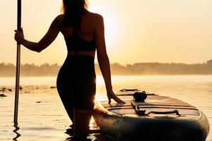 Majestic sunset, standing and looking. ...Young woman is with the sup board on the lake photo