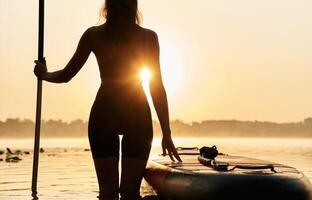 Black silhouette, sunset, illuminated,, Young woman is with the sup board on the lake photo