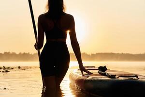 Majestic sunset, standing and looking.,. Young woman is with the sup board on the lake photo