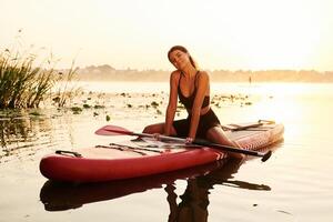 Positive, ,joyful,, facial expression. Young woman is with the sup board on the lake photo