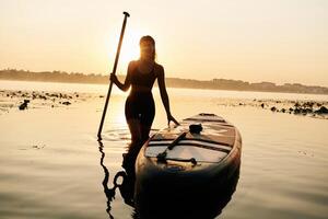 Calm, and ,peaceful, standing and posing. Young woman is with the sup board on the lake photo
