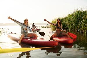 Active weekend, on the water.. Women friends are on sup board on the lake together photo