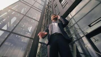inferior Visão sorridente bem sucedido o negócio homem falando Móvel telefone feliz discutir trabalhos acordo com Smartphone homem de negocios masculino Falando celular consultando cliente comunicar dentro cidade perto escritório construção video