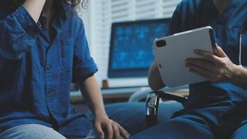 A man and woman sitting in a chair with a tablet video