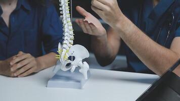 A doctor and a patient are looking at a model of the spine video