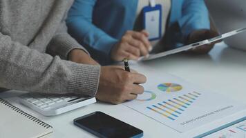 A man and woman are working on a document with graphs and charts video
