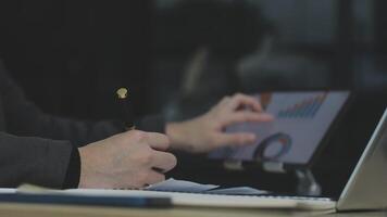 A person is using a pen and laptop to write on a graph video