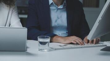 A man and woman sitting at a desk with a computer video