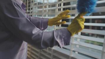 A person in a yellow glove cleaning blinds with a mop video