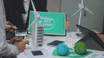 People sitting around a table with a net zero sign video