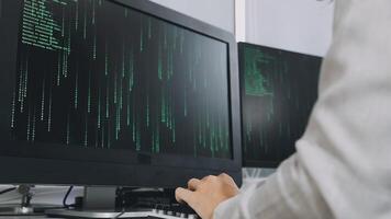 A person typing on a computer screen with green code on it video