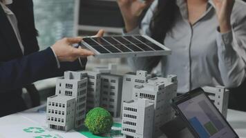 Two people are holding a laptop and a tablet with a model of a building video