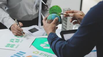 A man and woman are working on a paper with a green globe video