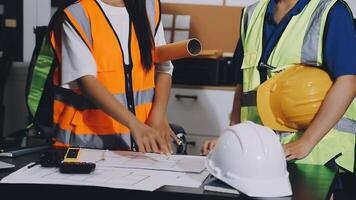 Two construction workers standing at a table with blueprints video