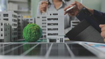A man is looking at a model of a building with a green tree video