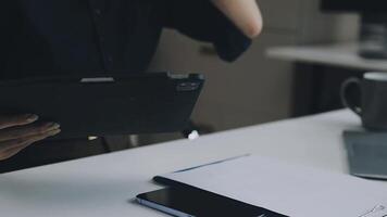 A person is holding a tablet computer and a notebook video