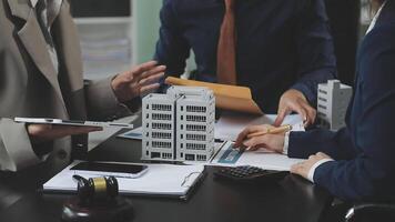 Business people discussing a project with model of a building video