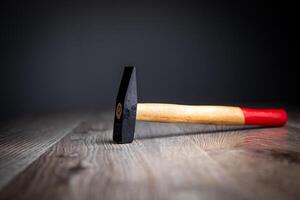 A hammer on a wooden table with a red handle photo