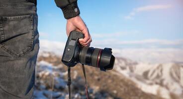 A person holding a camera on top of a mountain photo