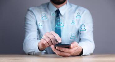 A man in a business suit is using a smart phone with social icons photo