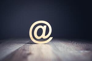 Email symbol on wooden table with dark background photo