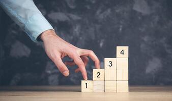 A person is placing wooden blocks on a table with numbers photo