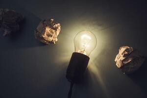 A light bulb and crumpled paper on a dark background photo