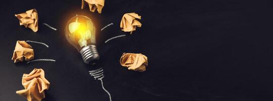 A light bulb surrounded by paper and crumpled up paper photo