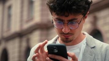 nachdenklich Reisender Tourist verwirrt ethnisch spanisch Mann mit Handy, Mobiltelefon Telefon Karte Navigation suchen Adresse Navigator Anwendung online hat verloren im Stadt Smartphone Ort suchen um Kerl männlich draußen video