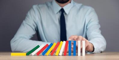 Businessman playing dominoes with colorful blocks photo