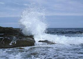 a wave crashing into the rocks photo