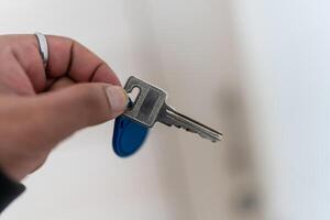 A photo of a hand gripping a key in front of a blurred background