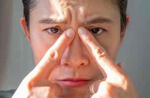 Portrait of unhappy Asian woman pointing to an acne occur between her eyebrows. photo