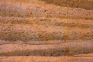 An earthen wall texture of clay house structure. These walls are constructed by ramming a mixture of aggregates, including gravel, sand, silt and a small amount of clay. photo
