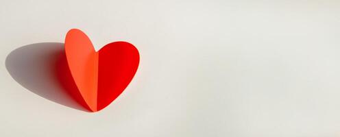 Banner with paper decoration in the shape of a red heart on a white background. Flat plan, top view, space for text on the right side. photo