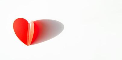 Banner with paper decoration in the shape of a red heart on a white background. Flat plan, top view, space for text on the right side photo