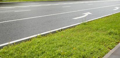 Asphalt roadway with an arrow pointing to the end of the lane pointing to the left. photo