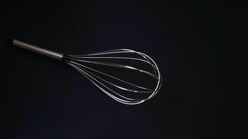 Stainless steel whisk on black background photo